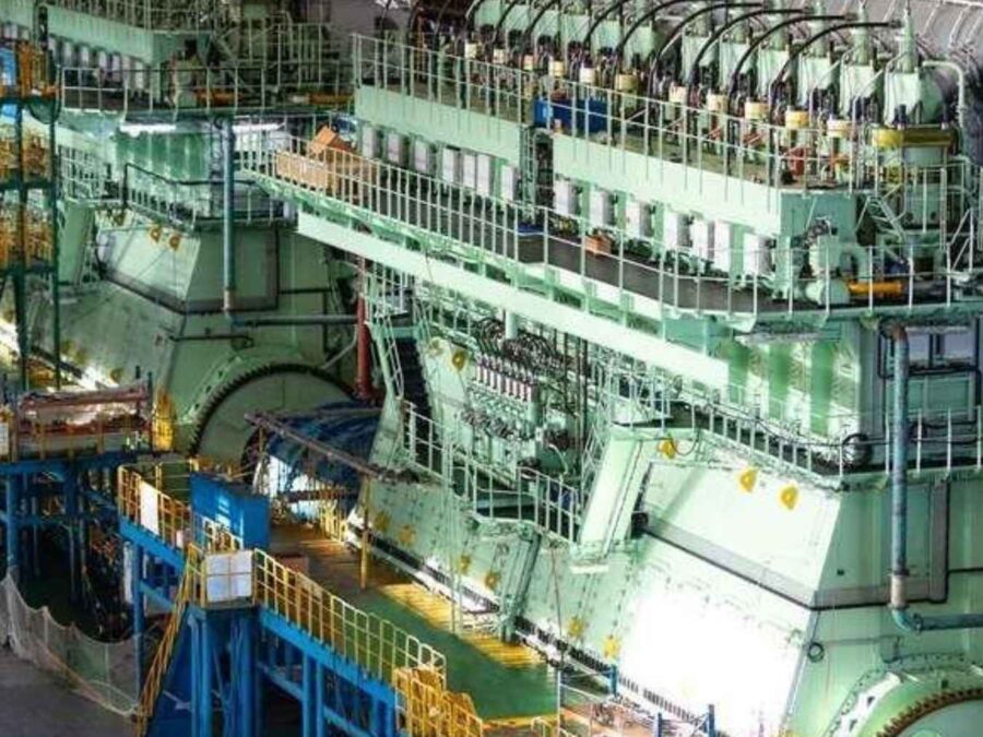 A large methanol dual-fuel engine undergoing assembly and testing in a shipyard workshop.