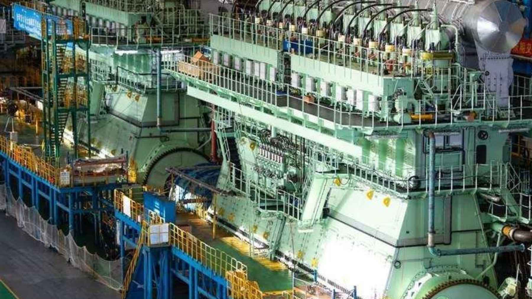 A large methanol dual-fuel engine undergoing assembly and testing in a shipyard workshop.